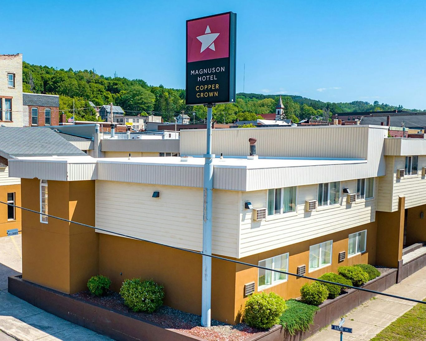 Magnuson Hotel Copper Crown exterior view with signage and blue sky.