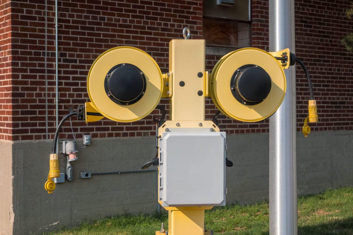 Yellow dual electric cable reel mounted outside brick building in Hancock, Michigan.