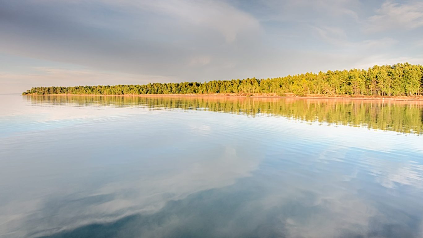 Calm waters and tree-lined shoreline of Lake Superior near Magnuson Hotel Copper Crown.