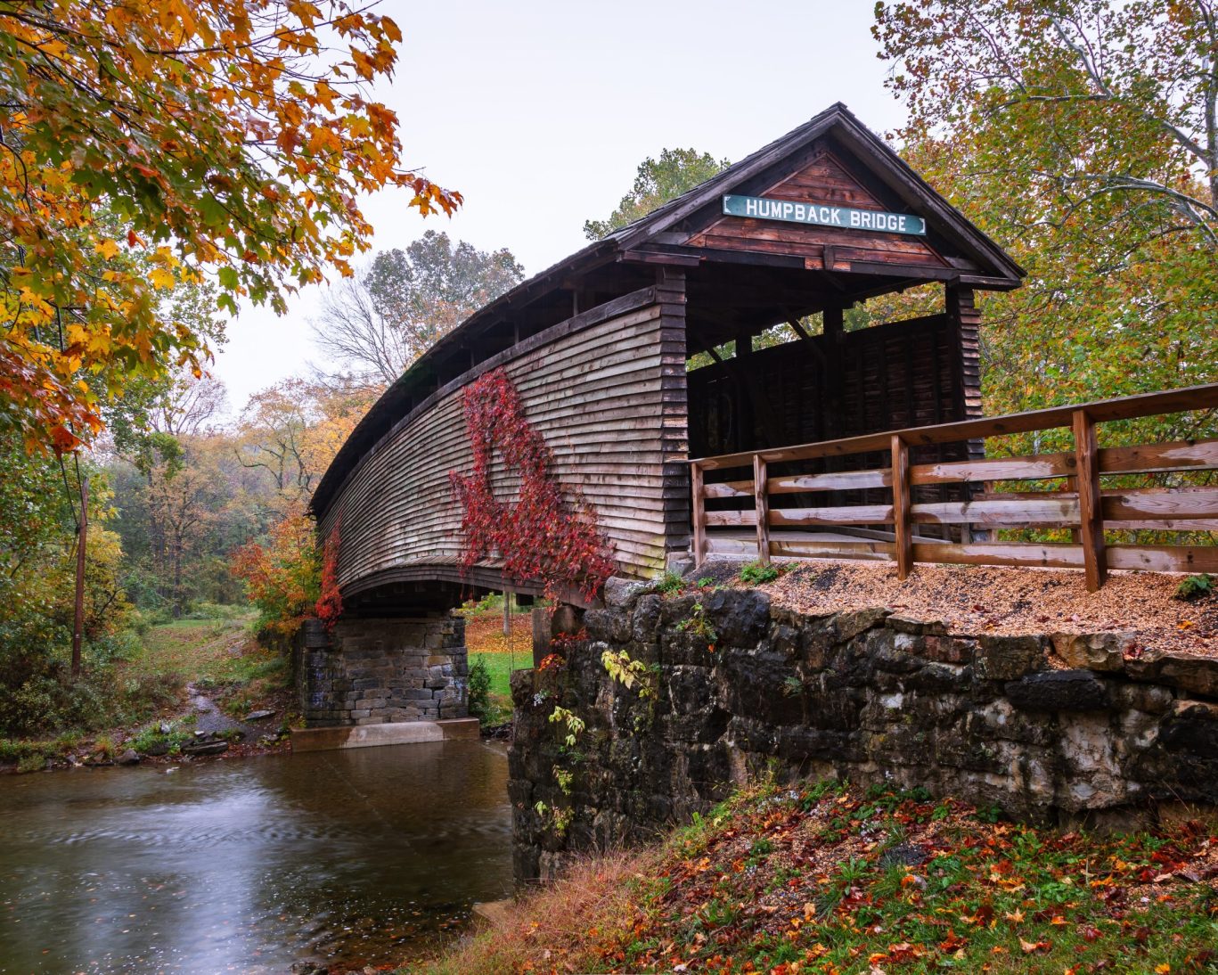 Historic Humpback Covered Bridge in Covington, Virginia surrounded by fall foliage.