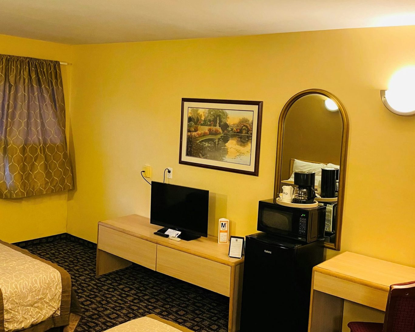 Cozy hotel room at M Star Hotel Mansfield featuring a TV, microwave, and work desk.