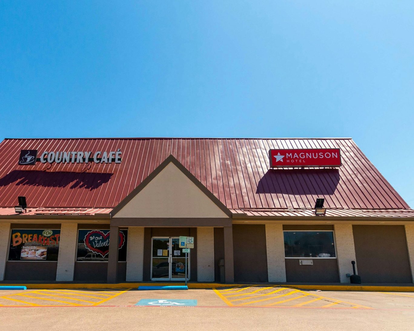 Exterior of Magnuson Hotel and Country Café under clear blue Texas sky.