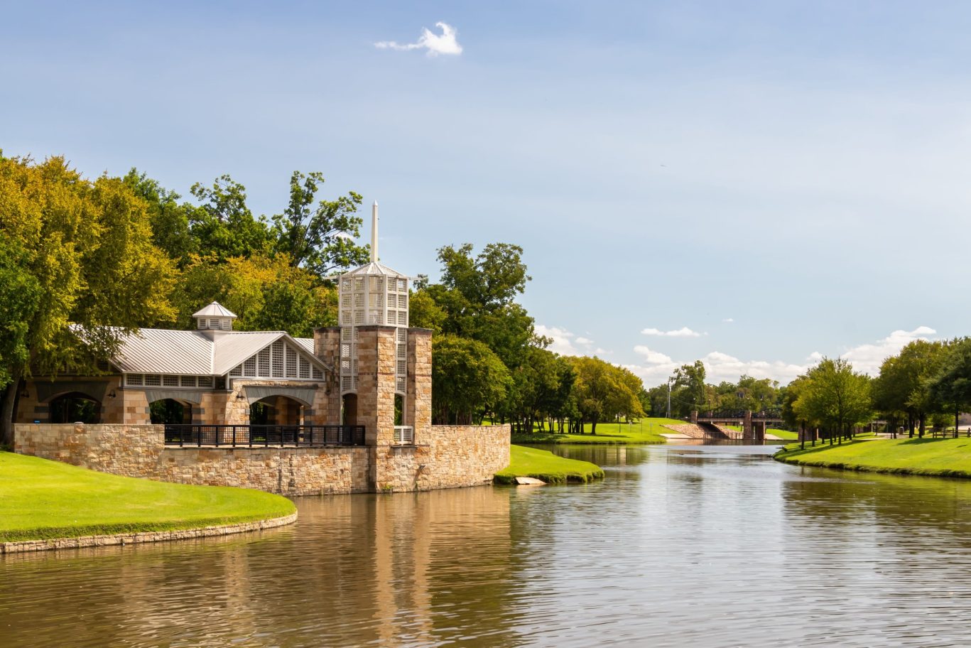 Stone pavilion overlooking calm river in a landscaped park setting in Irving, Texas.