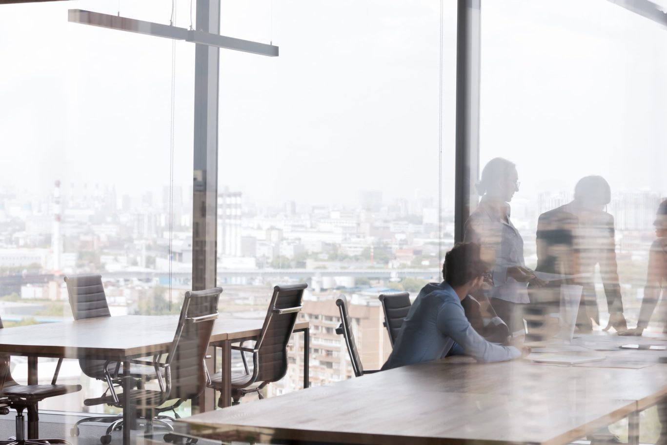 Team meeting in high-rise conference room with panoramic city skyline views.