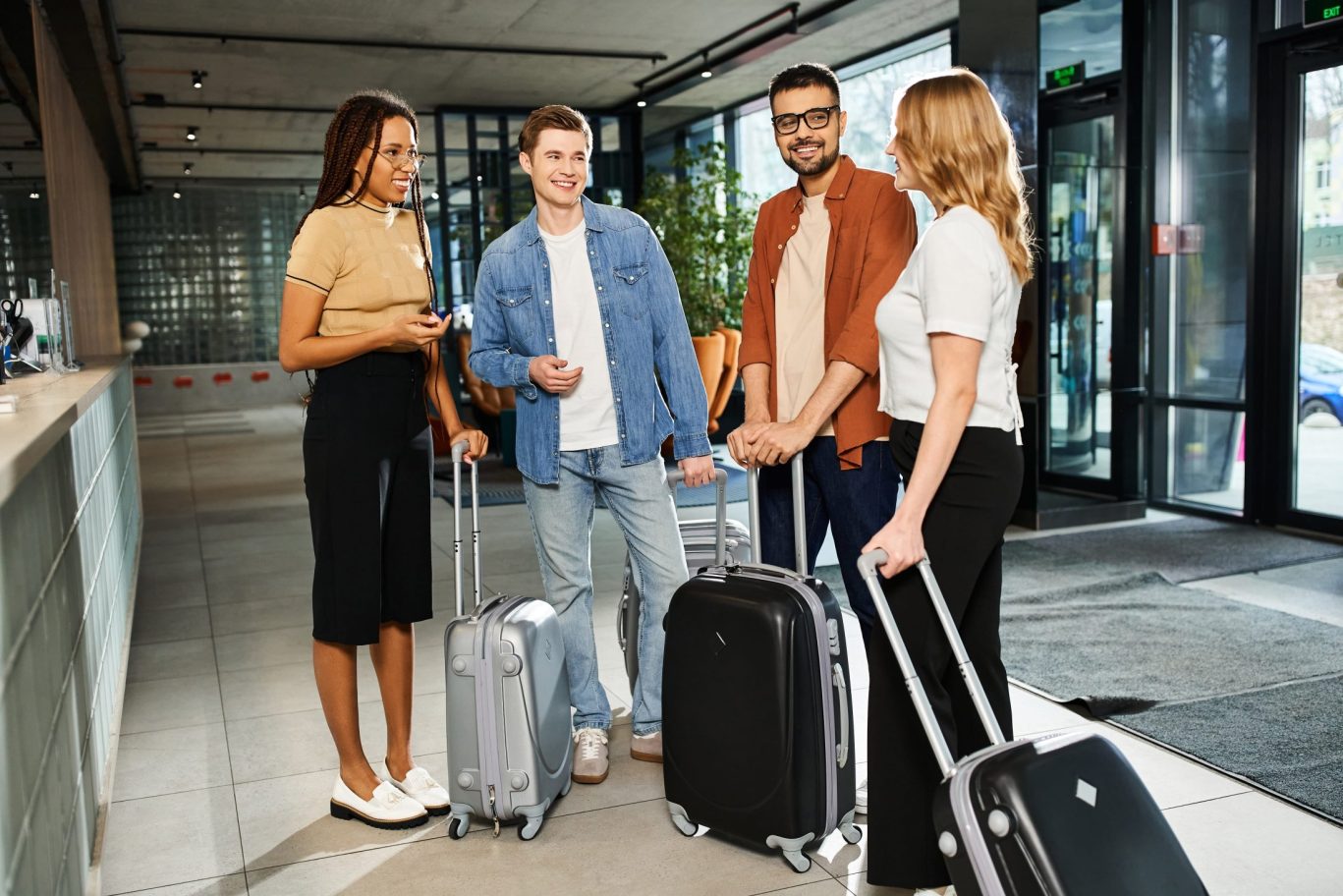 Diverse group of young travelers arriving at hotel lobby with luggage and smiles.