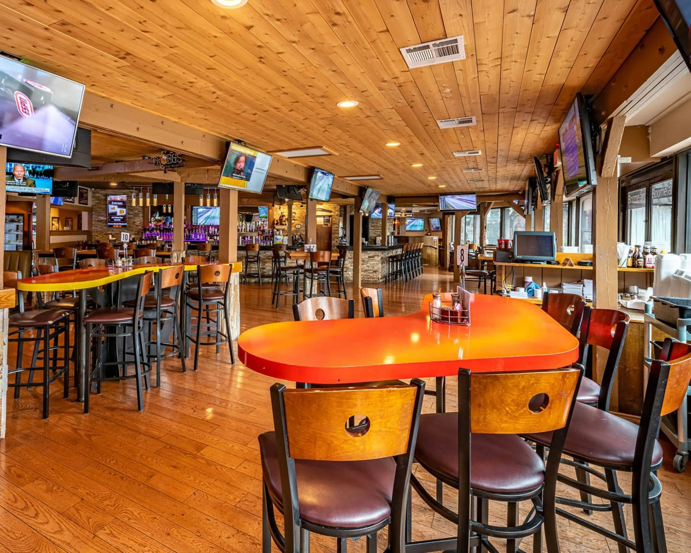 Spacious rustic sports bar with wood interior, TVs, and high-top tables for casual dining and entertainment.
