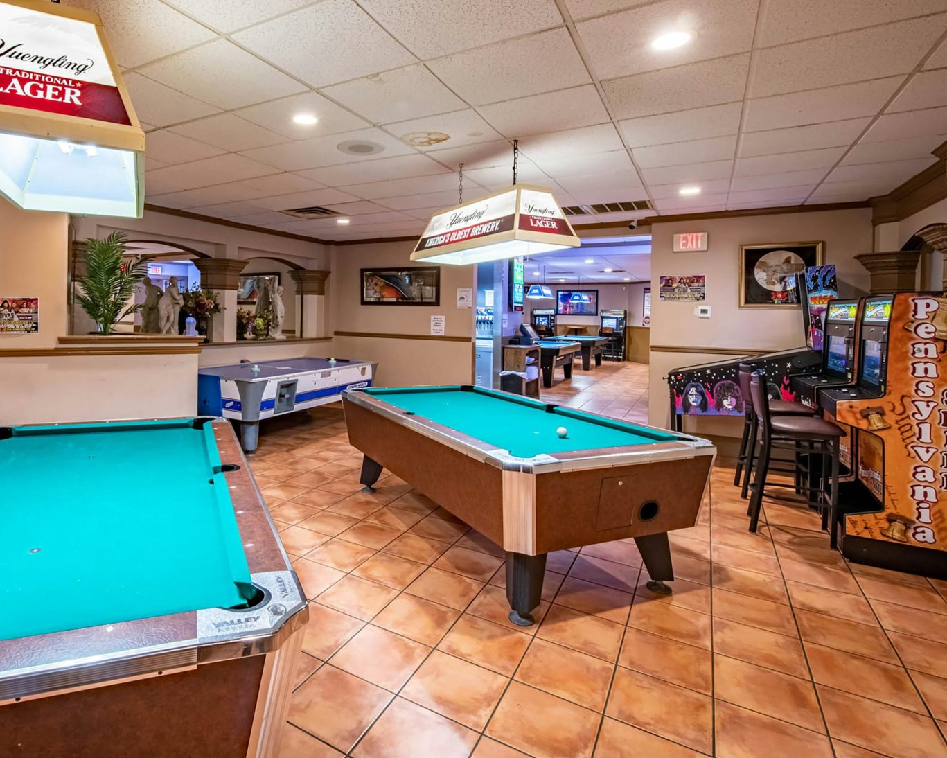 Hotel game room featuring pool tables, arcade machines, and air hockey for guest entertainment.