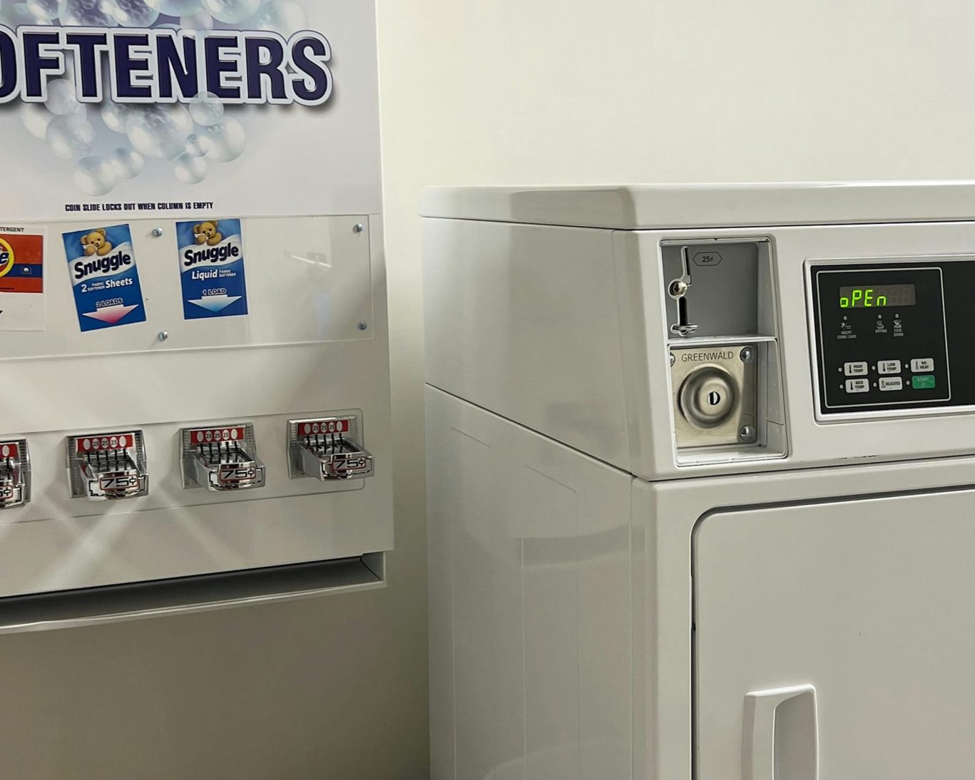 On-site coin laundry area with detergent vending machine and modern dryer for hotel guest use.