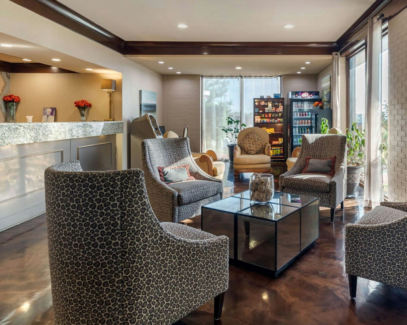 Comfortable hotel lobby with patterned armchairs, snack station, and reception desk.