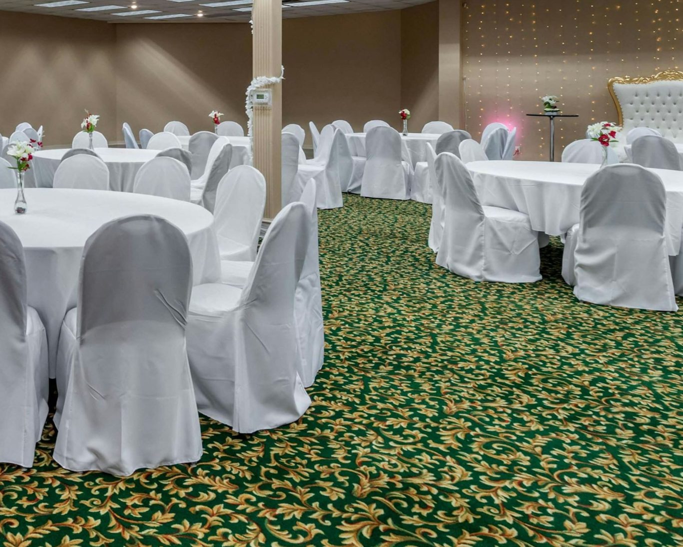 Hotel banquet hall set up for an event with round tables and white chair covers.