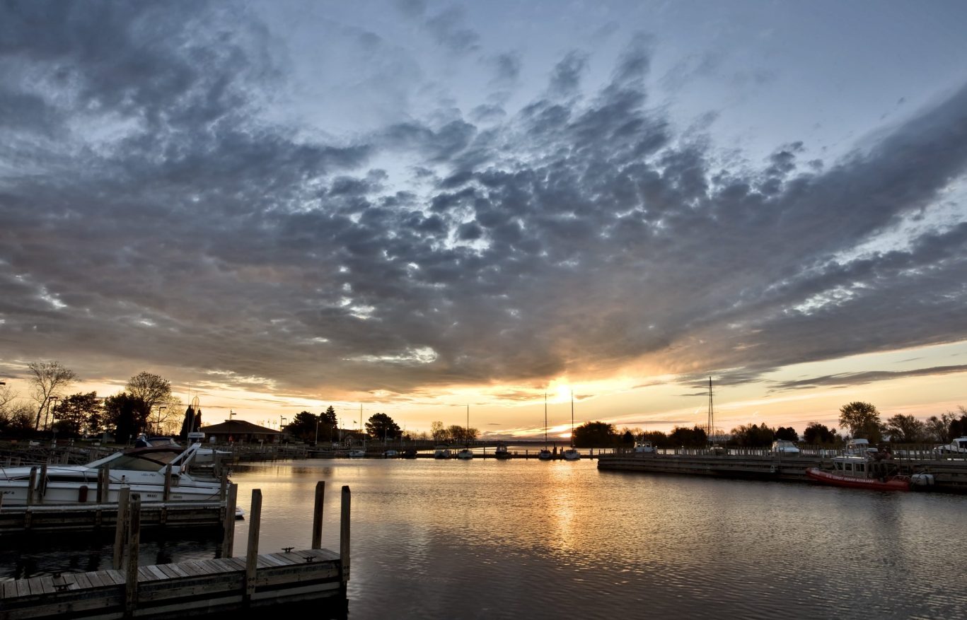 Golden hour sunset at Jamestown Marina with dramatic clouds and calm waters around the docks.