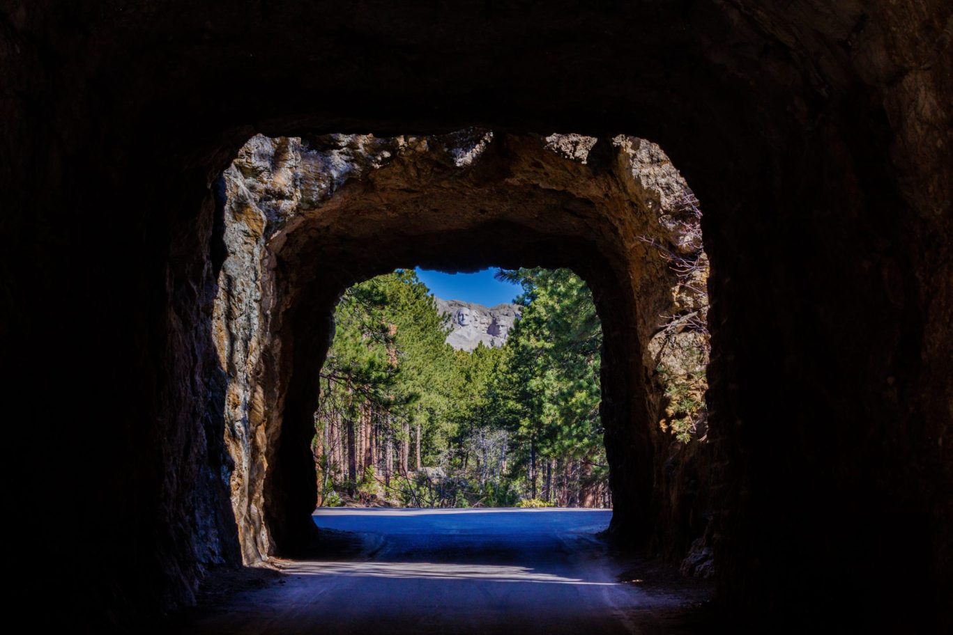 Framed view of Mount Rushmore through scenic rock tunnel along the Iron Mountain Road.