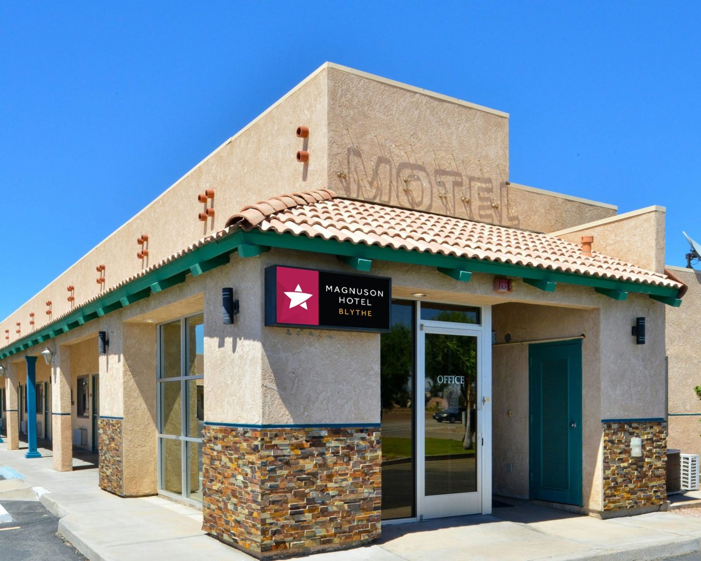Front exterior of Magnuson Hotel Blythe with logo signage under a clear blue sky.
