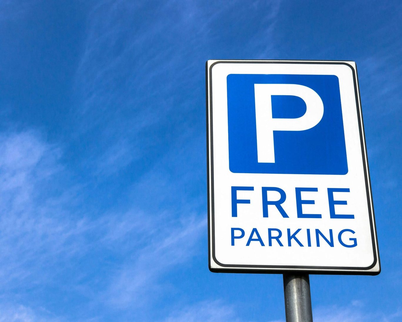 Free parking sign against a bright blue sky outside Magnuson Hotel Blythe.