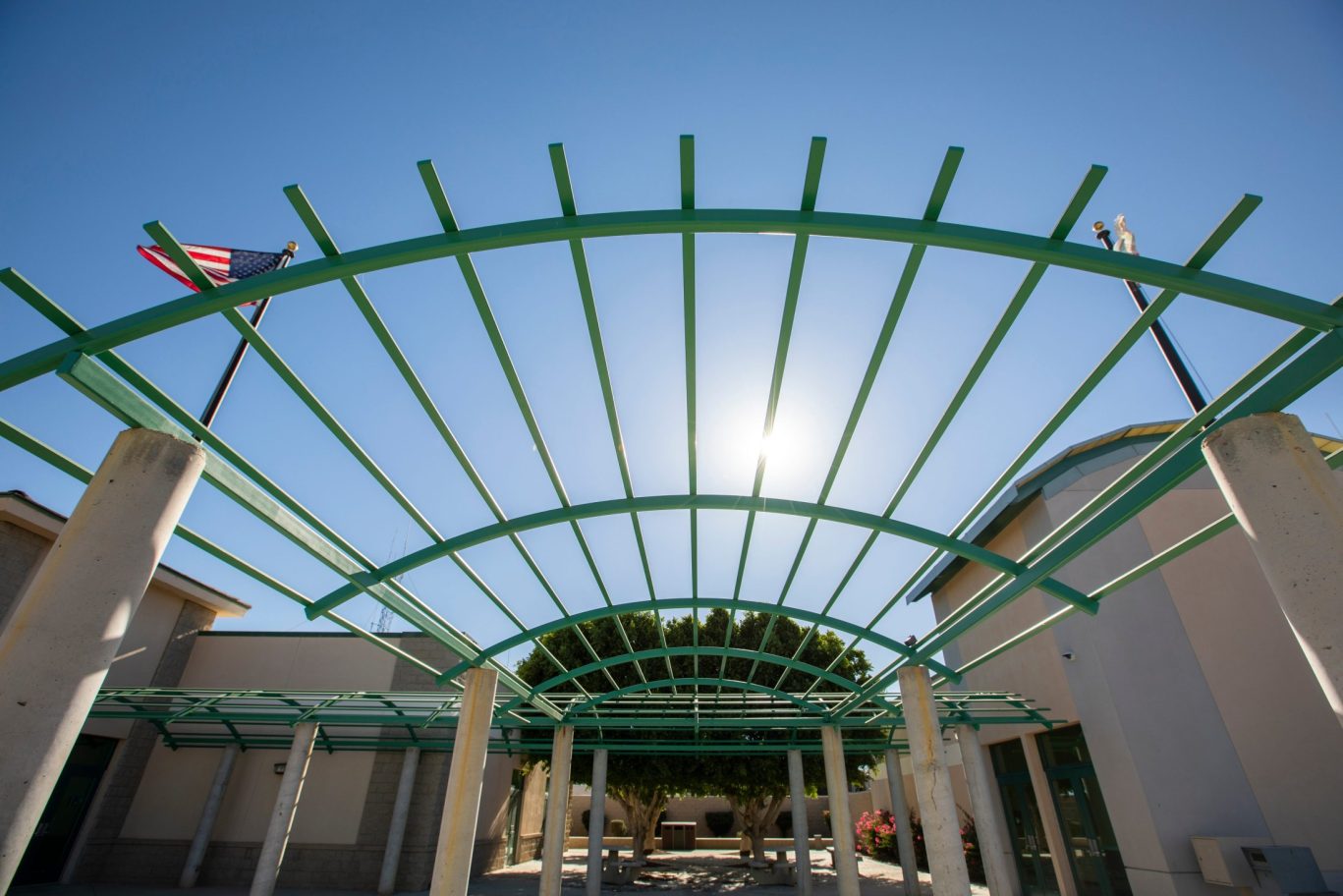 Civic building courtyard with teal metal trellis and American flag in Blythe, California.