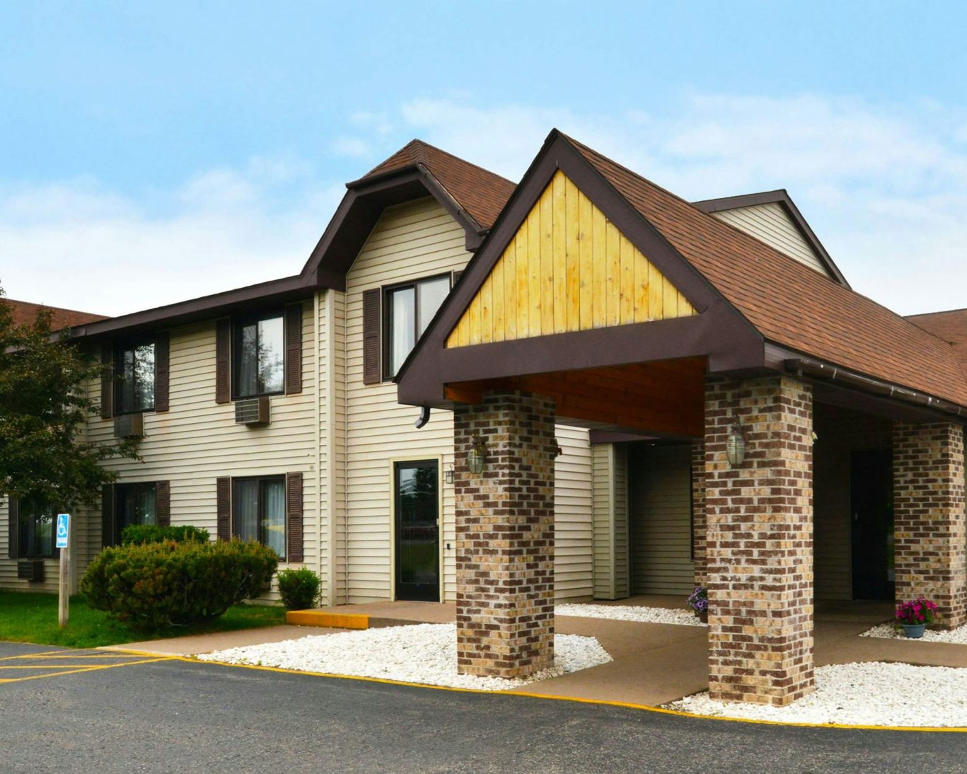 Exterior view of Magnuson Hotel with brick entrance and accessible parking in front.
