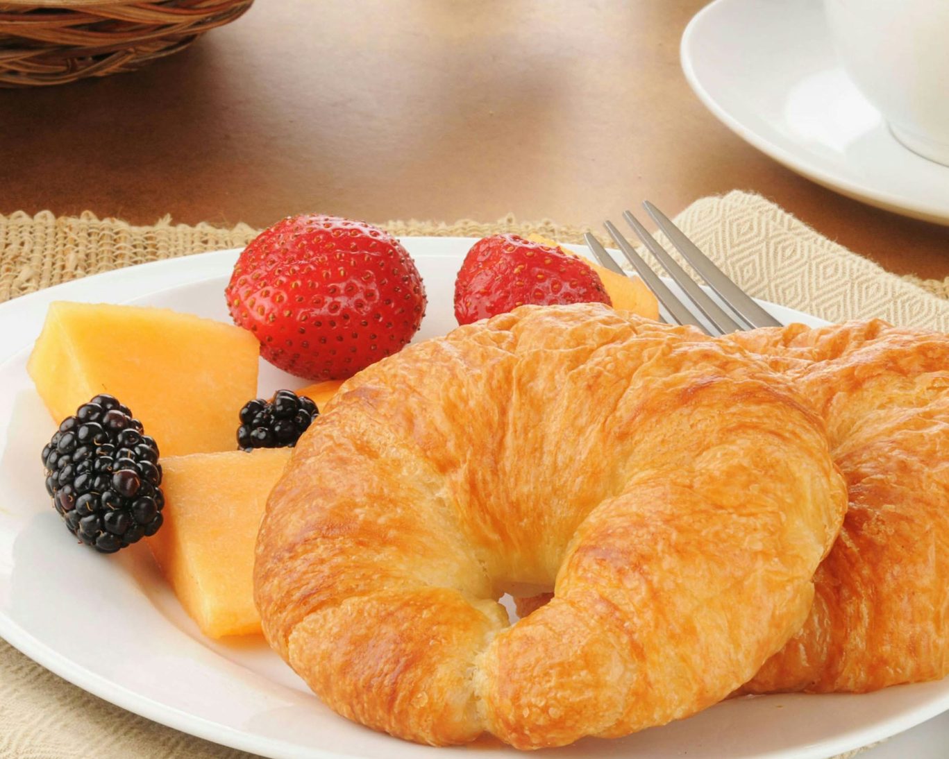 Fresh continental breakfast with croissants, strawberries, melon, and blackberries at Magnuson Hotel.