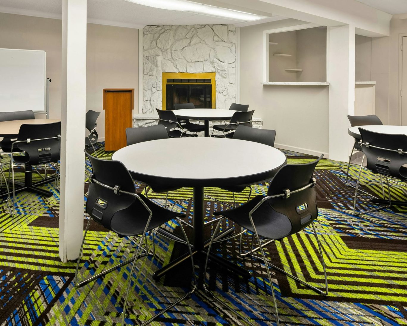 Colorful hotel meeting room with round tables and fireplace at Magnuson Hotel Detroit.