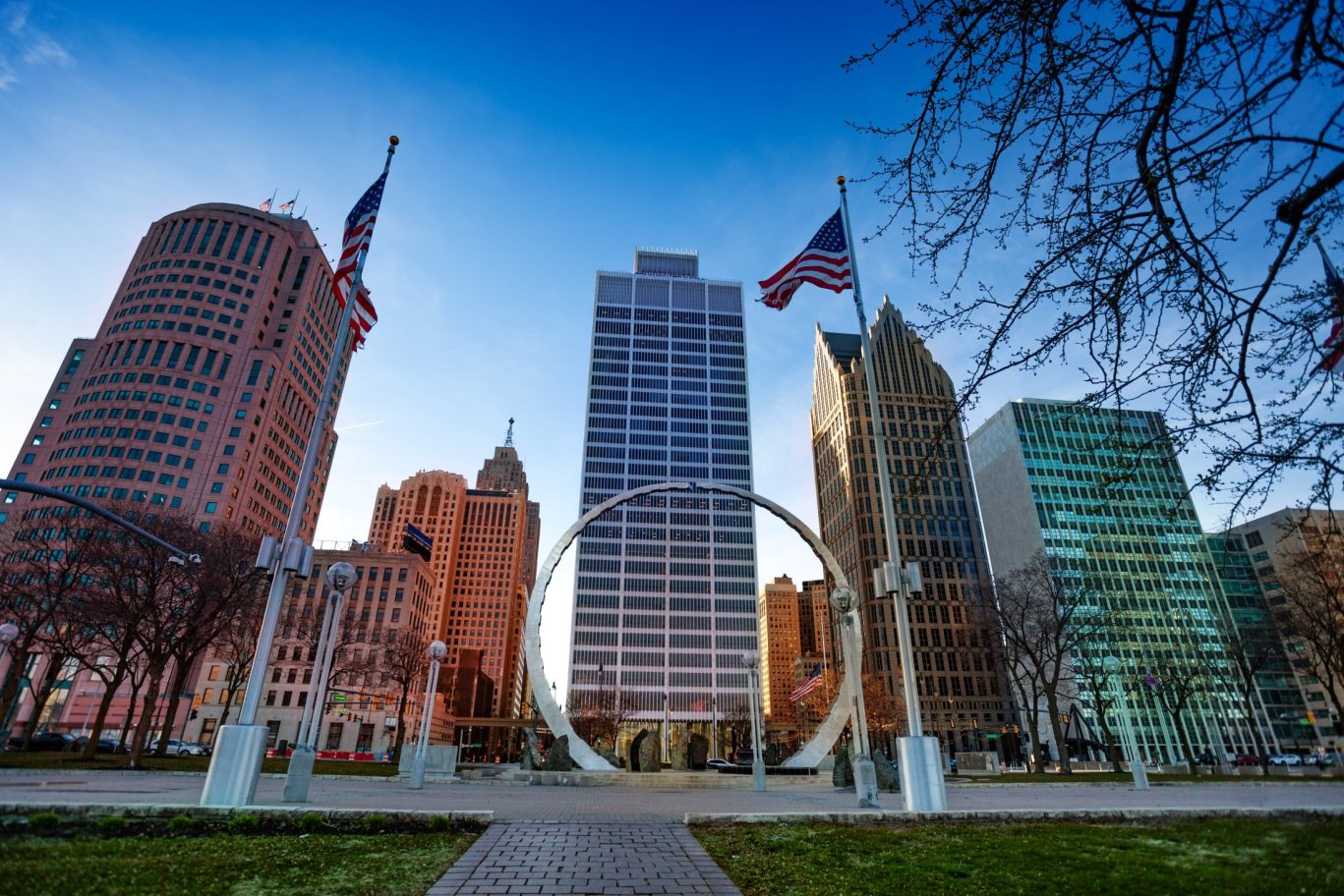Iconic Downtown Detroit skyline with circular monument and American flags.