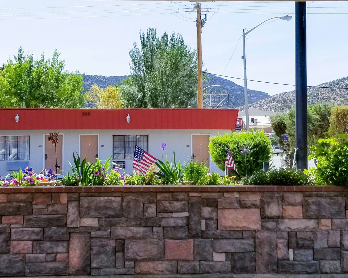 Charming motel-style hotel rooms with flower garden and American flags in Ely, Nevada.