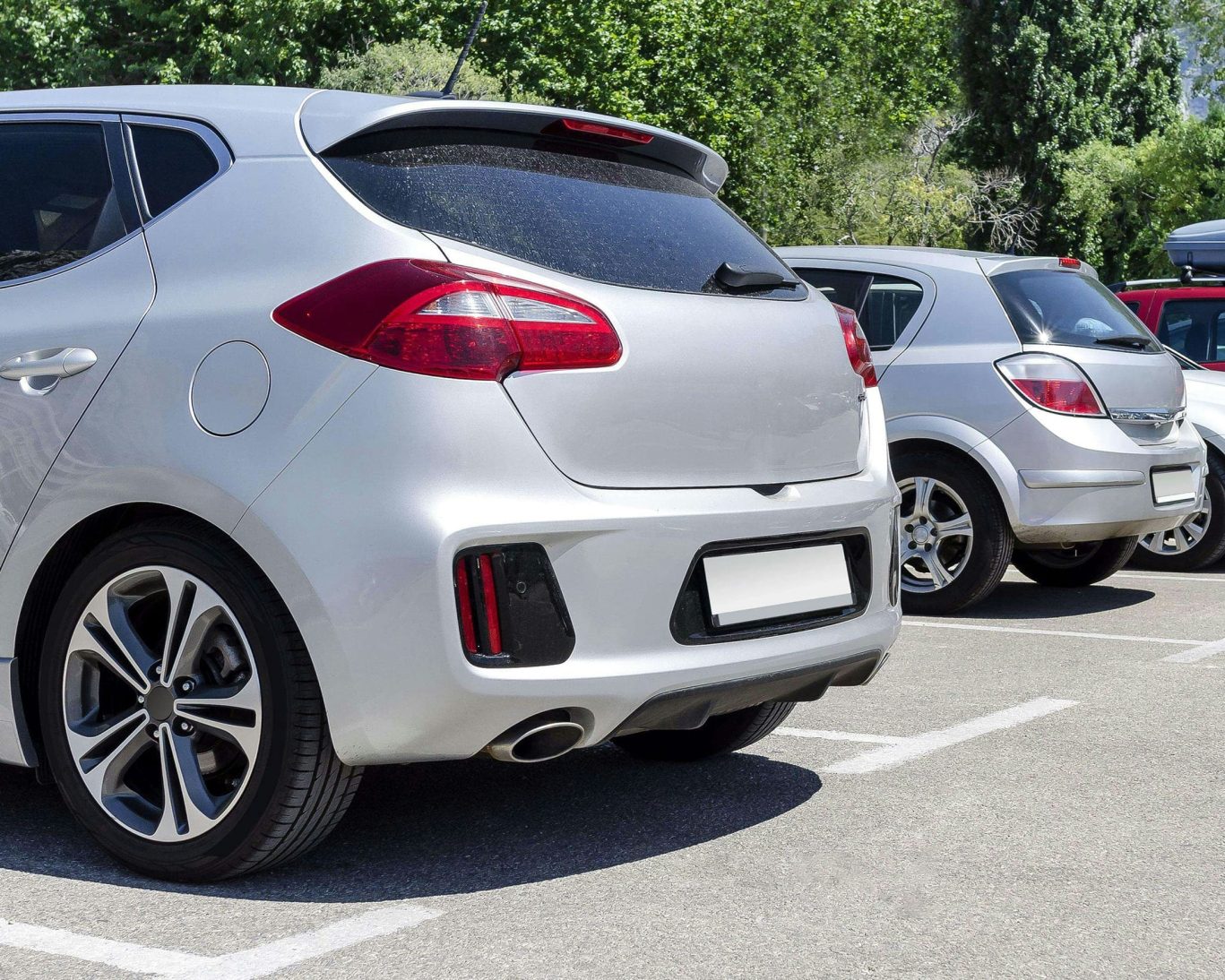 Close-up view of guest vehicles parked in a hotel parking lot on a sunny day.
