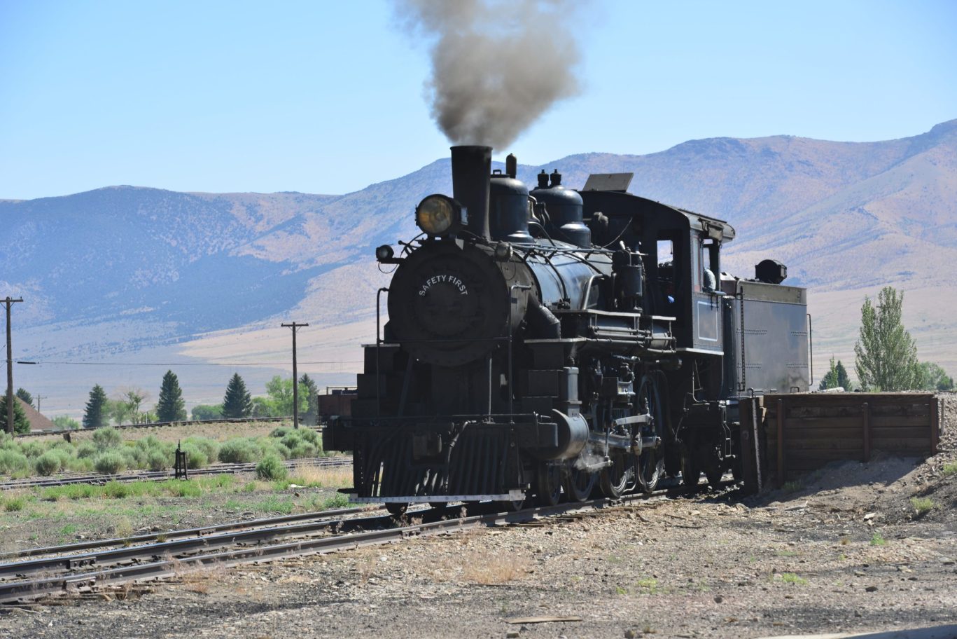 Black steam locomotive traveling through lush green forest on the historic 1880 Train route in South Dakota.