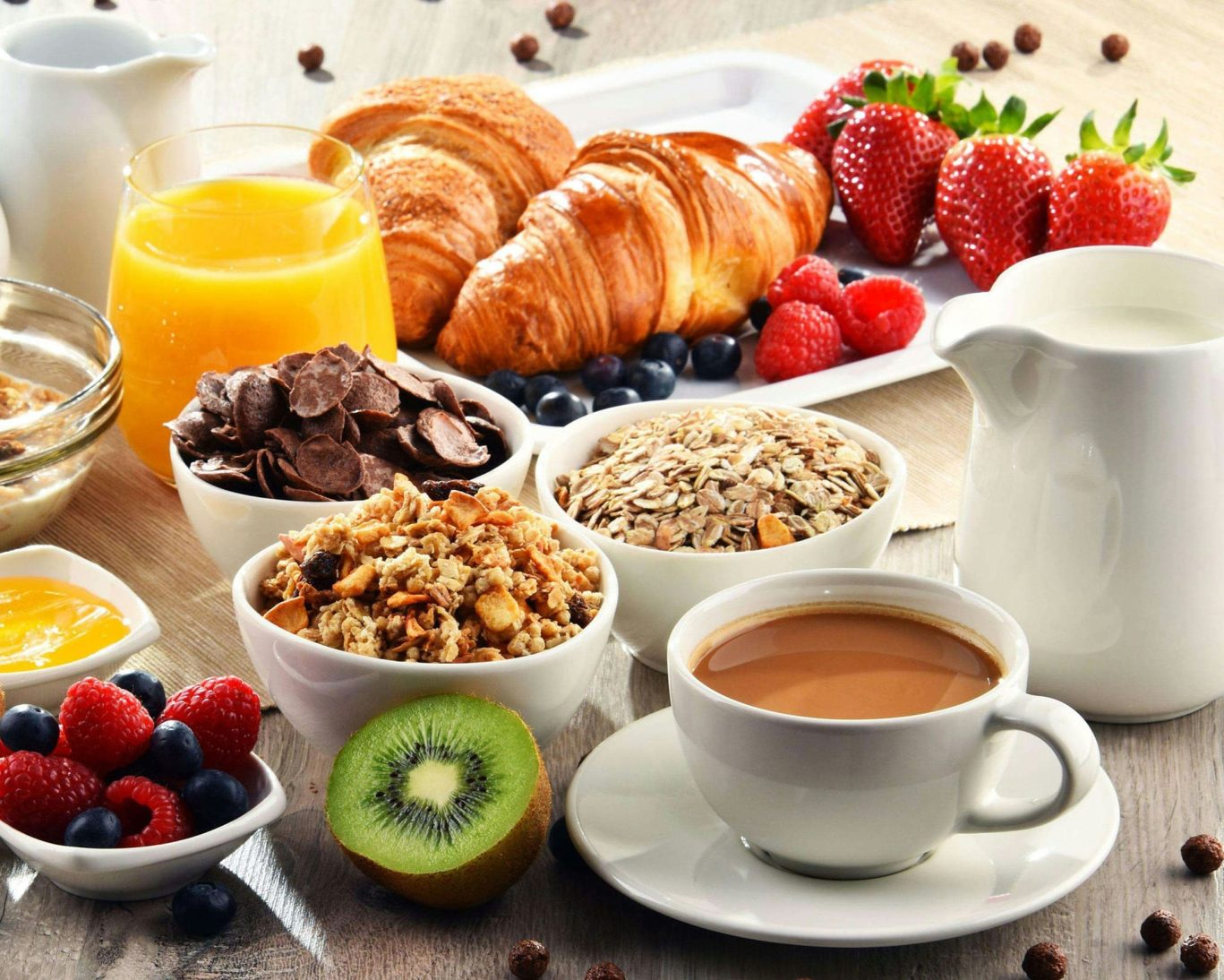 Healthy continental breakfast with croissants, fresh fruit, granola, cereal, juice, and coffee.