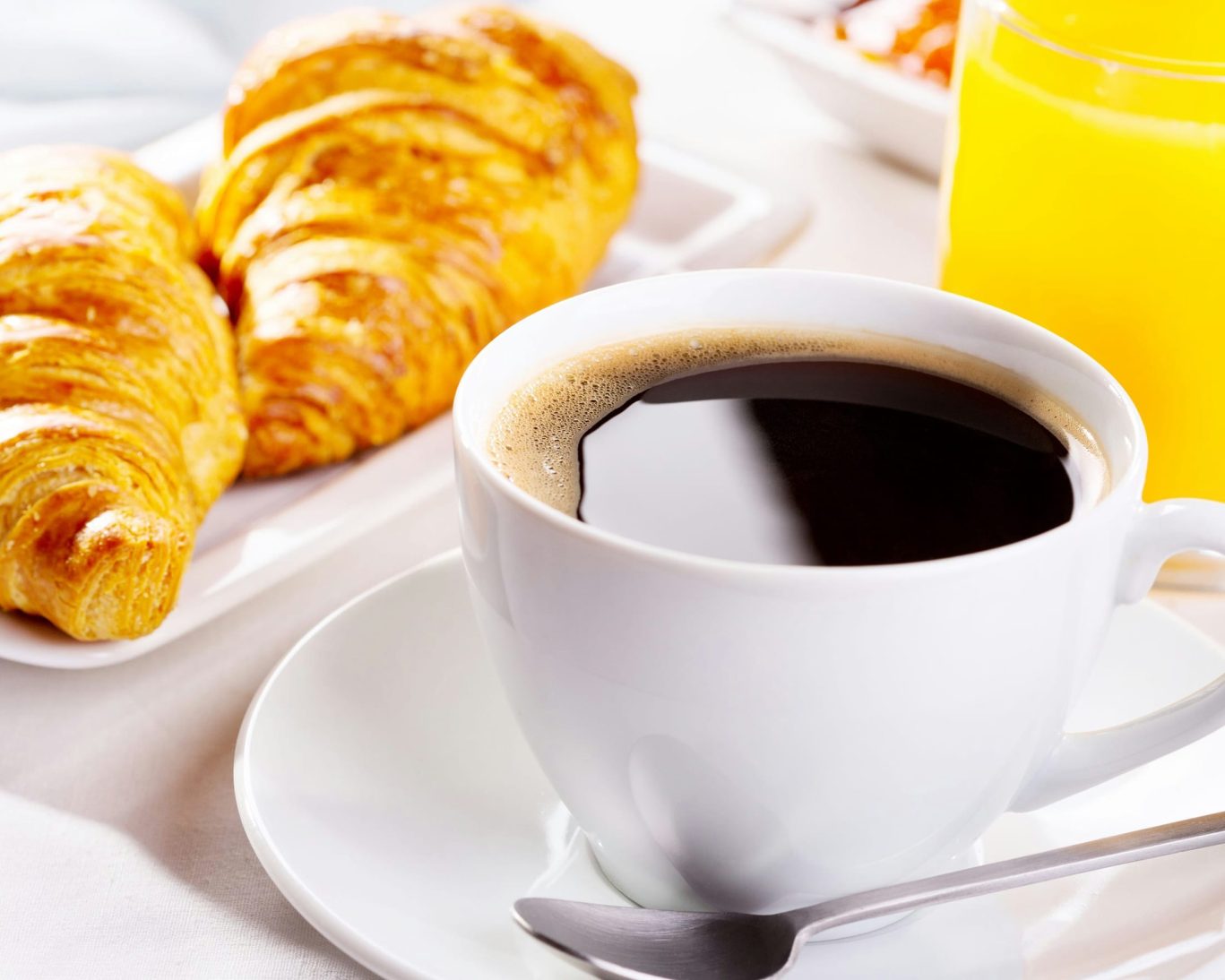 Complimentary hotel breakfast with fresh croissants, black coffee, and orange juice at Magnuson Hotel.