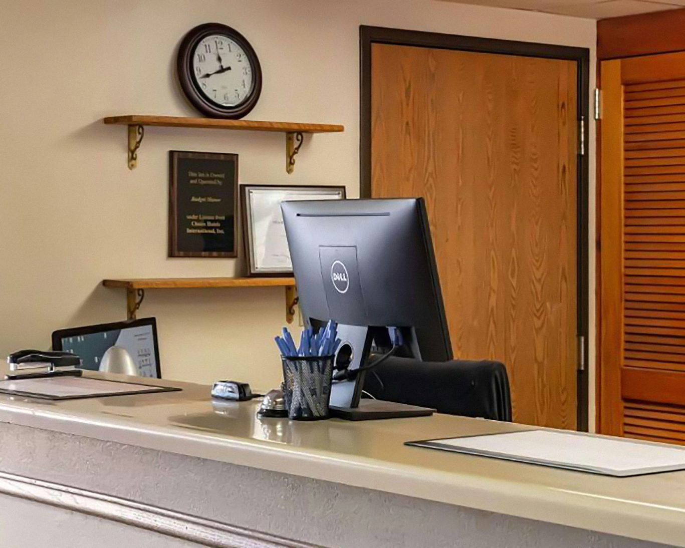 Hotel front desk with computer and clock at Magnuson Hotel reception area.