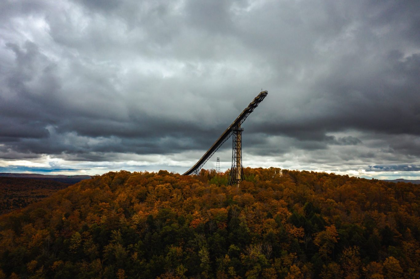 Copper Peak ski flying hill tower surrounded by autumn forest under dramatic skies in Michigan's Upper Peninsula.