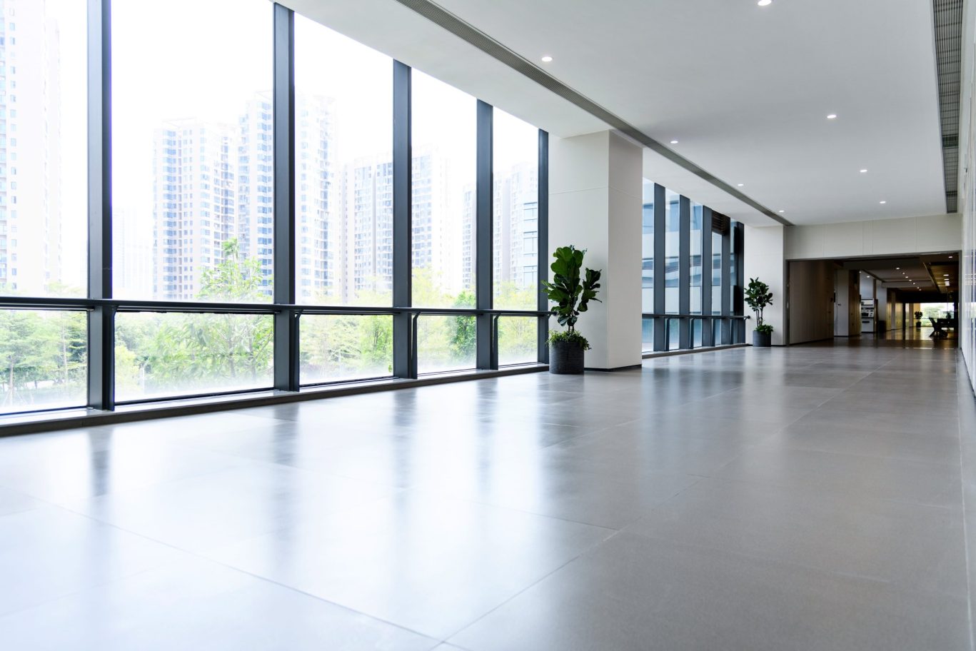 Bright hotel hallway with floor-to-ceiling windows overlooking the city skyline.