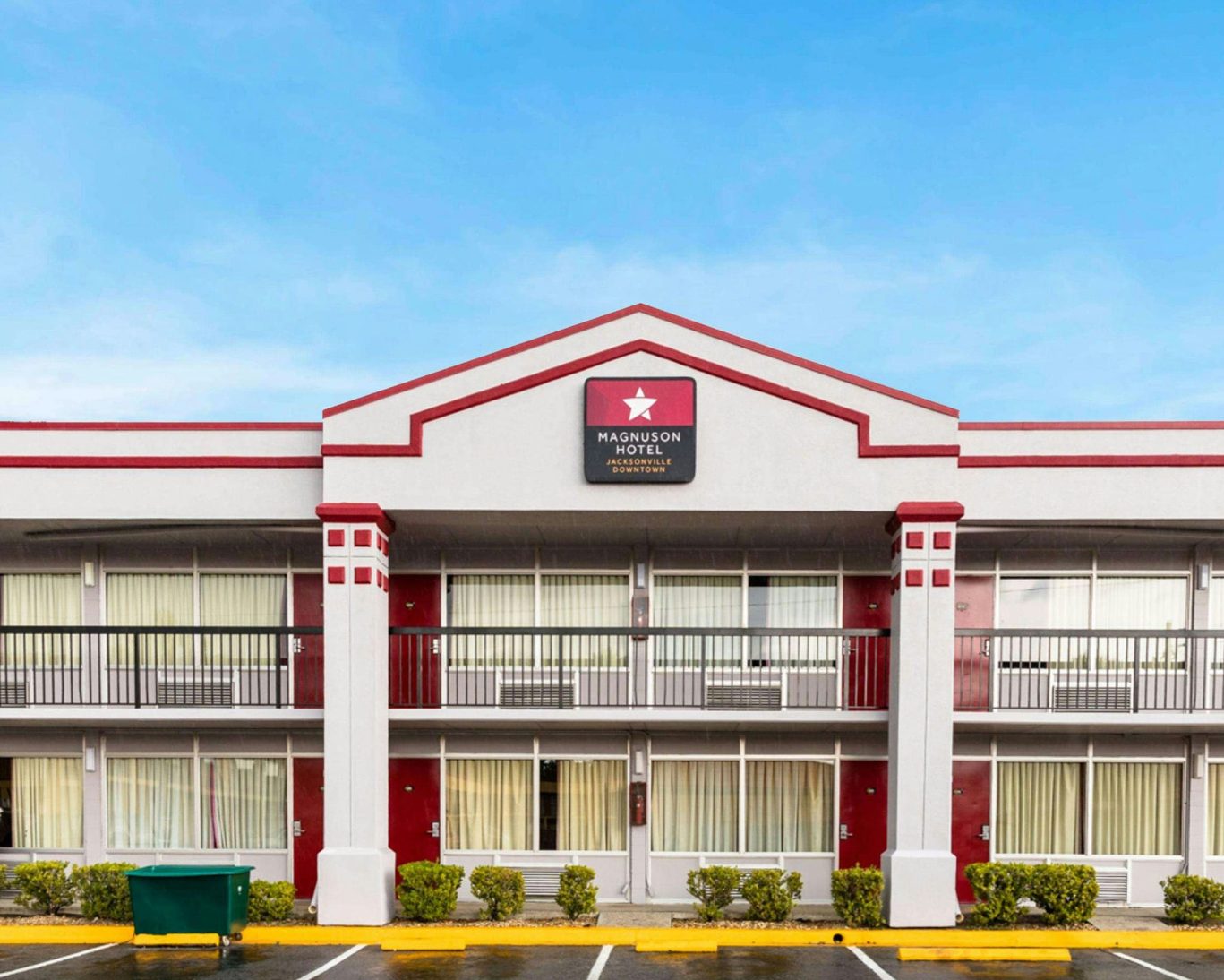Front exterior of Magnuson Hotel Jacksonville Downtown with two-story rooms and free guest parking.