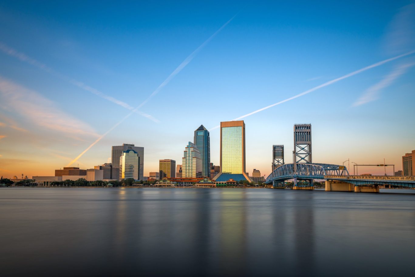 Downtown Jacksonville skyline at sunset with St. Johns River and Main Street Bridge in view.