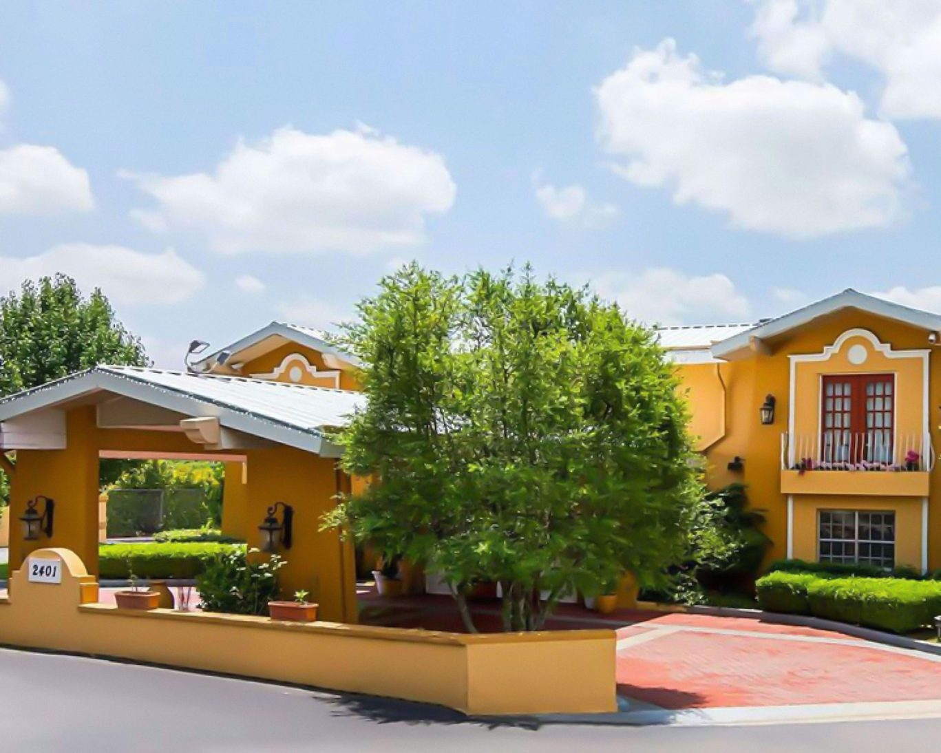 Sunny exterior of Magnuson Hotel with landscaping and welcoming entrance in Arkansas.