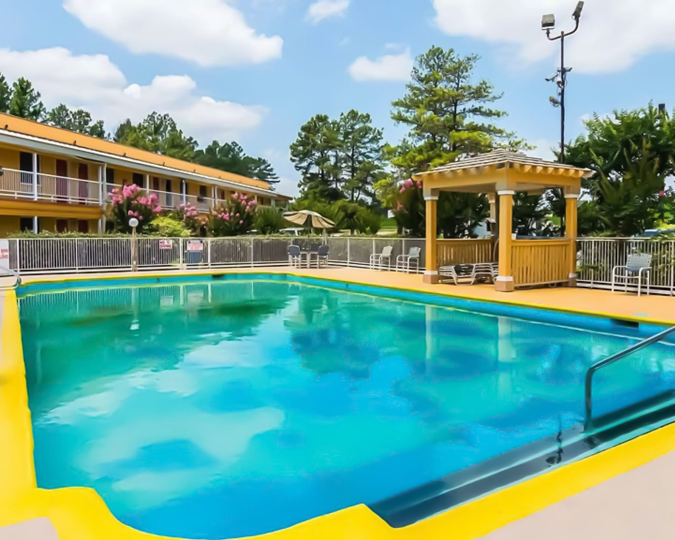 Outdoor swimming pool with shaded lounge area and deck chairs at Magnuson Hotel Arkansas.