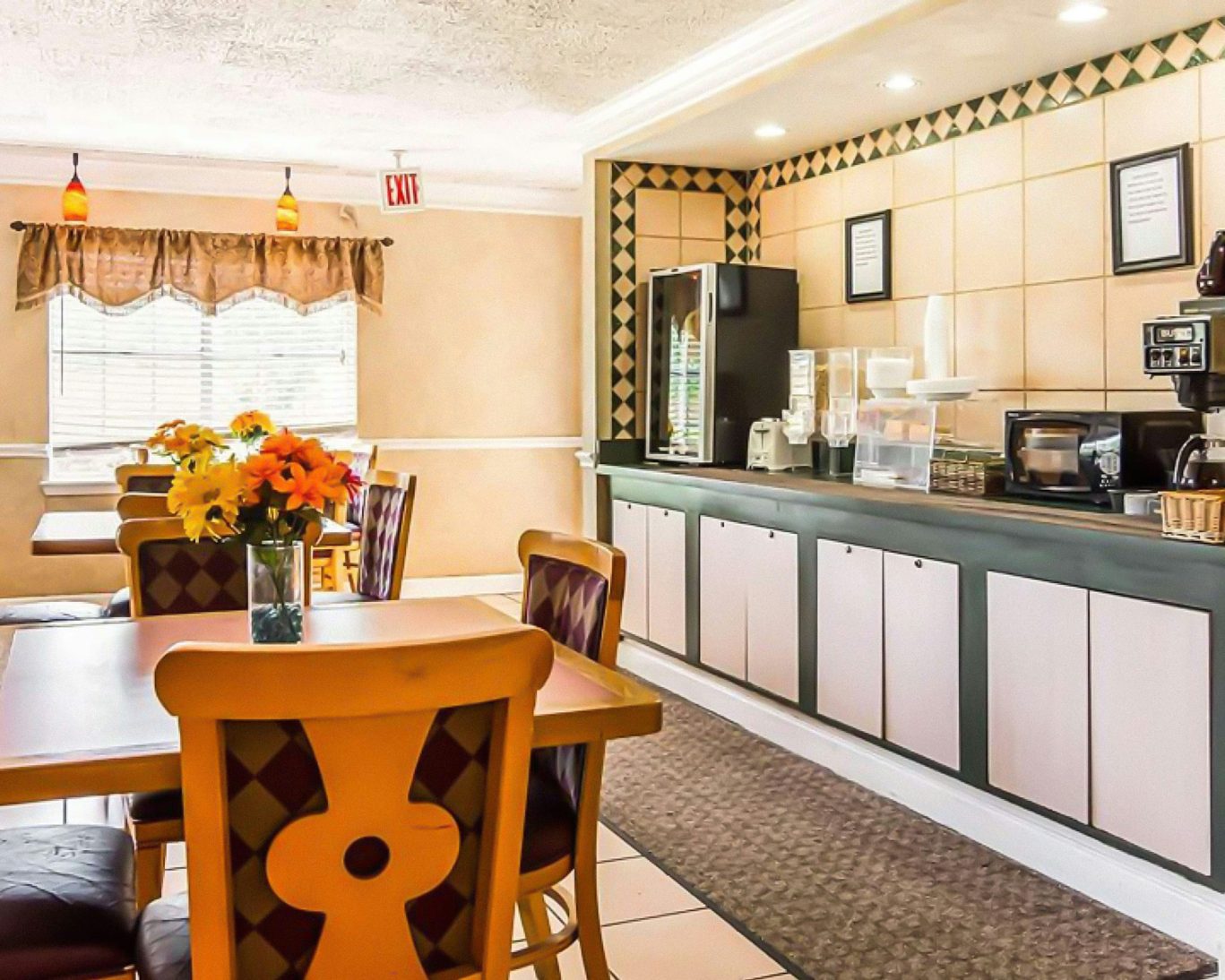 Casual breakfast dining area with self-serve food counter and tables at Magnuson Hotel.