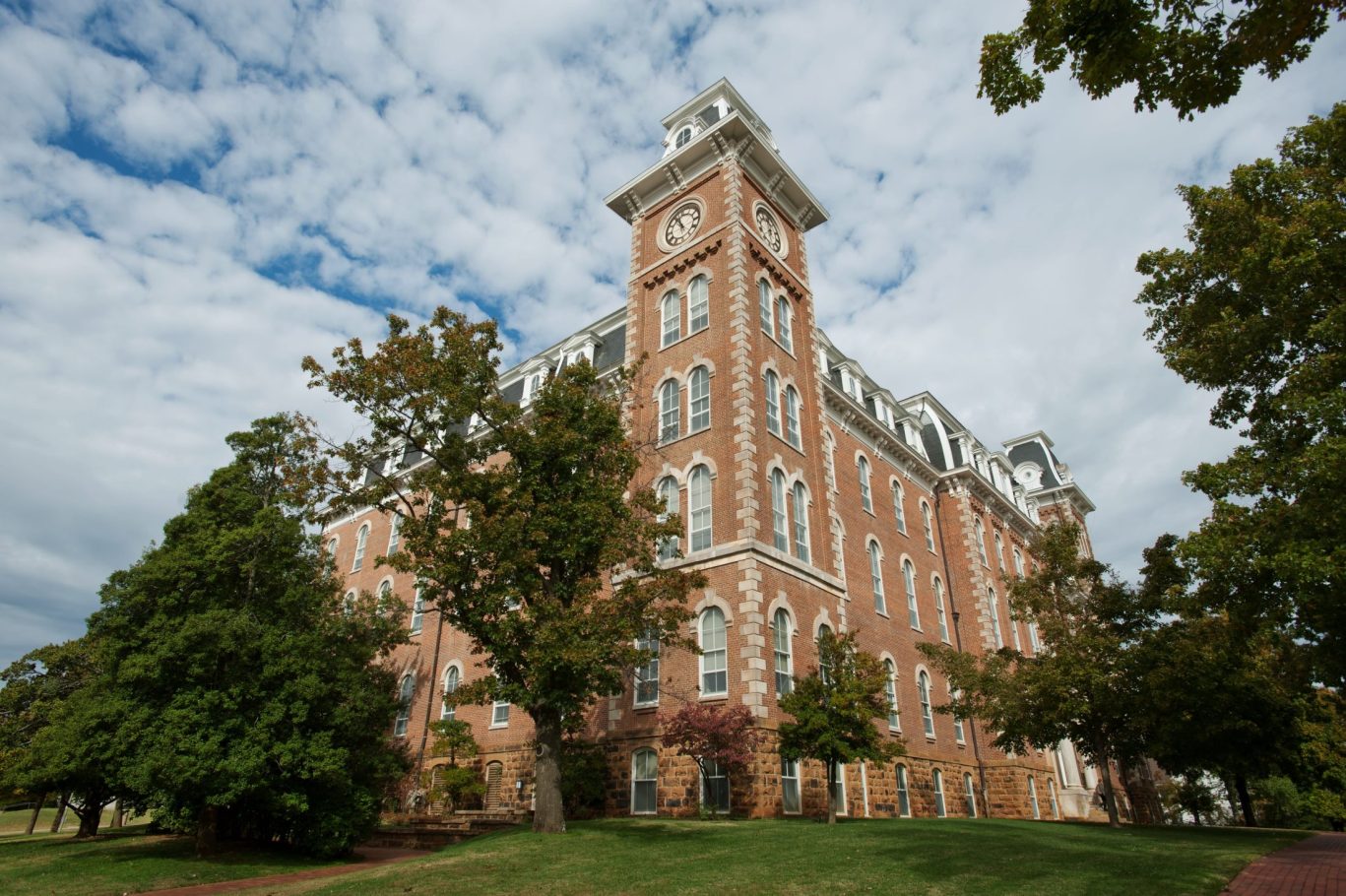 Old Main building at University of Arkansas in Fayetteville with historic red brick architecture and clock tower.