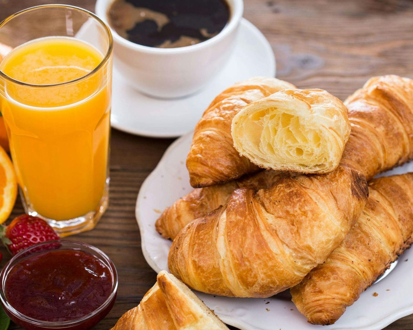 Close-up of continental breakfast with coffee, croissants, orange juice and jam.