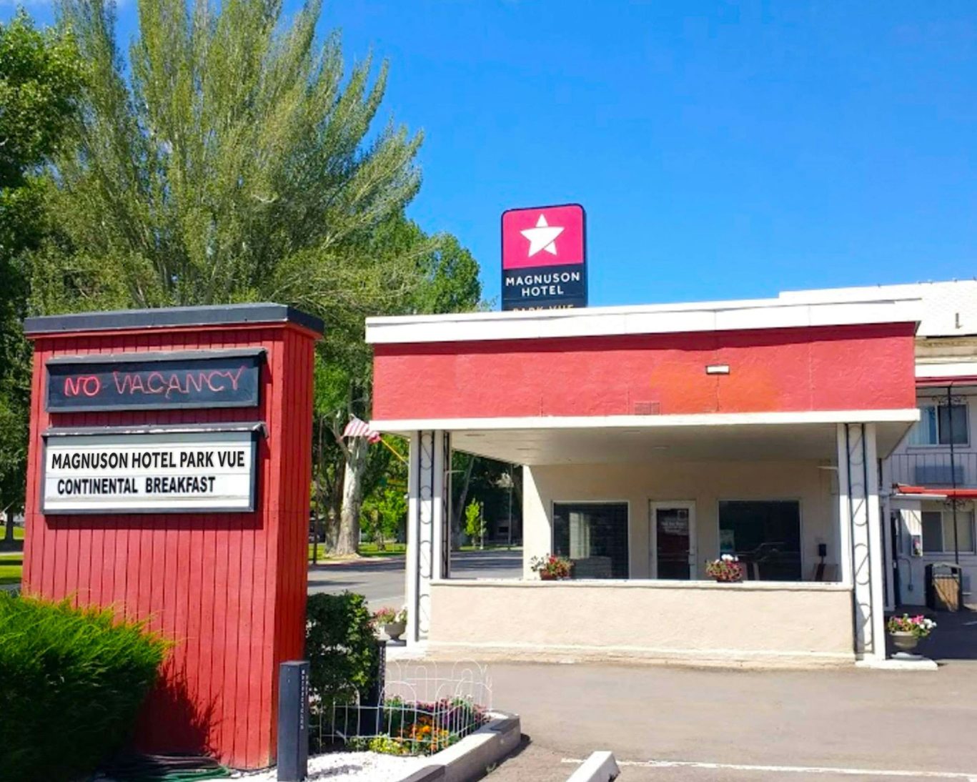 Exterior of Magnuson Hotel Park Vue with no vacancy sign under clear blue sky.