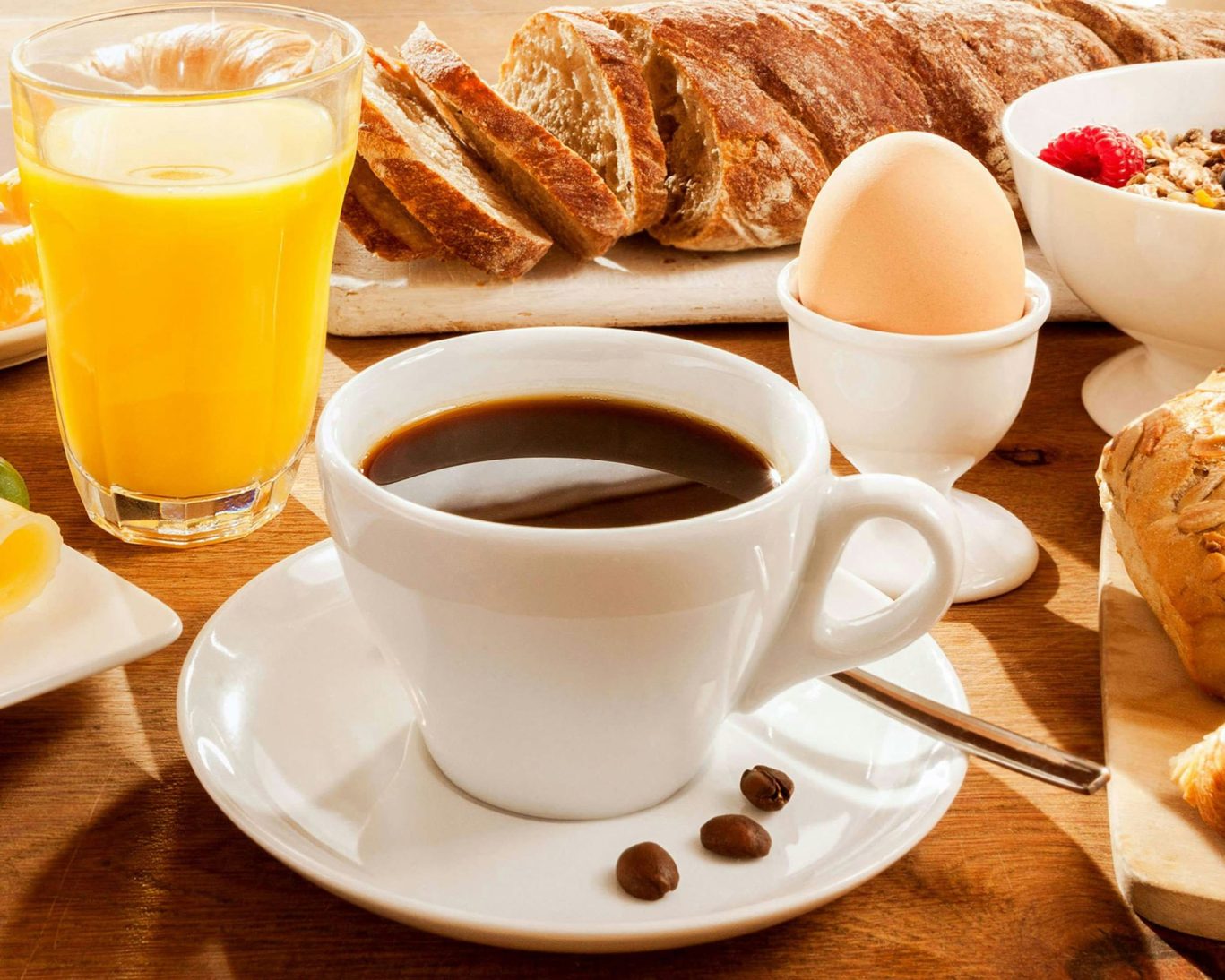 Fresh continental breakfast with coffee, orange juice, egg, bread, and pastries.