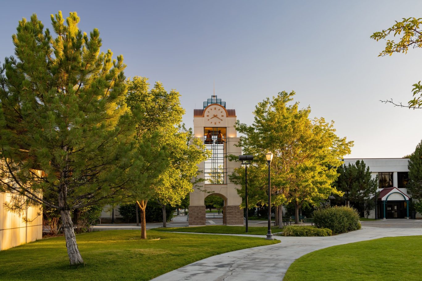 Clock tower and scenic walkway surrounded by green trees on a sunny day in Ely, Nevada.