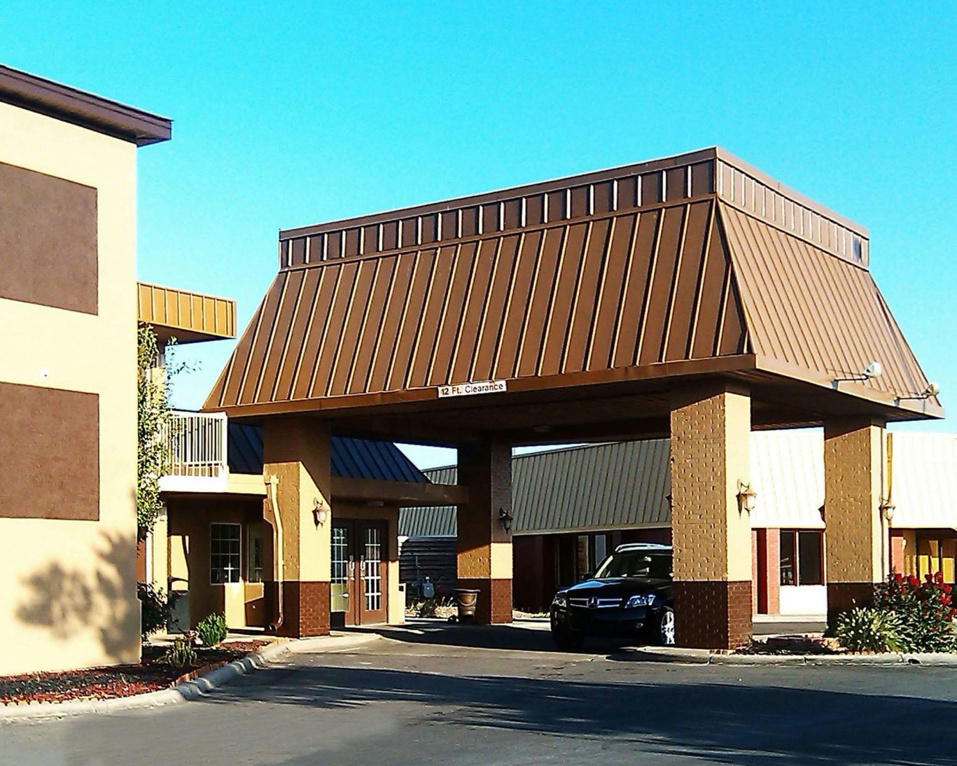 Exterior view of Magnuson Hotel with covered entrance and guest vehicle arrival area.