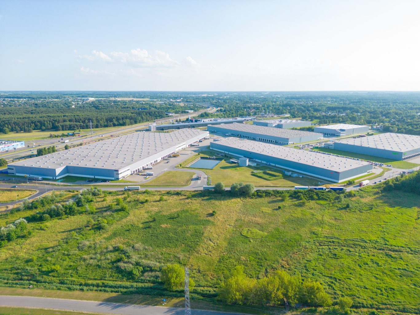 Large industrial warehouse and distribution center surrounded by grassy fields.