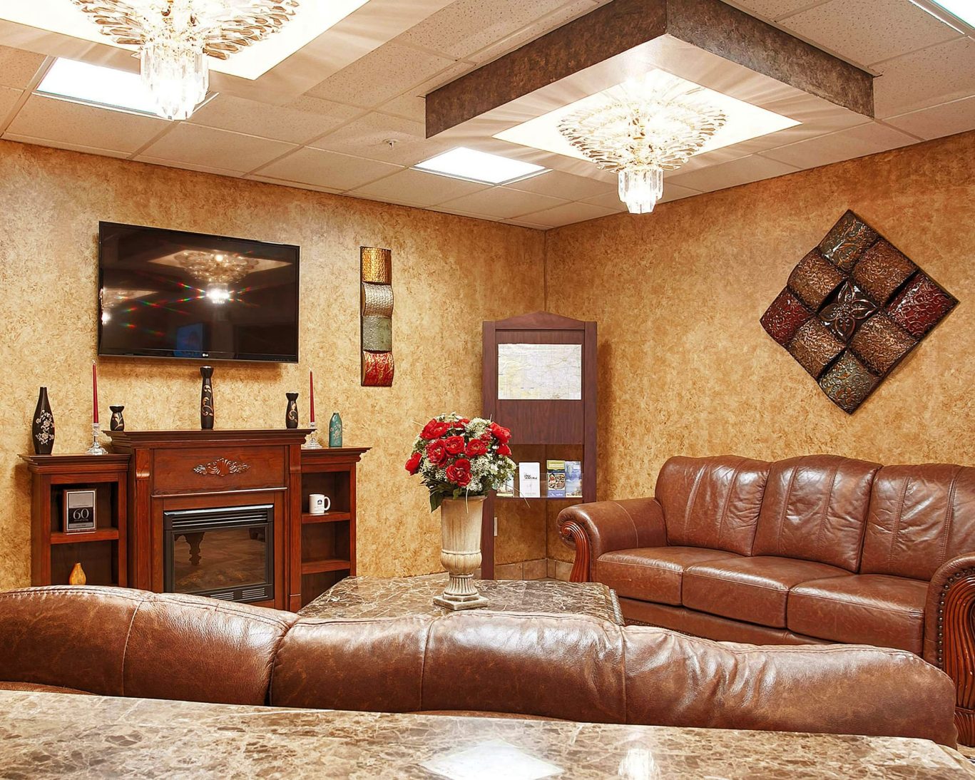 Cozy hotel lounge with leather sofas, marble tables, and flat-screen TV.