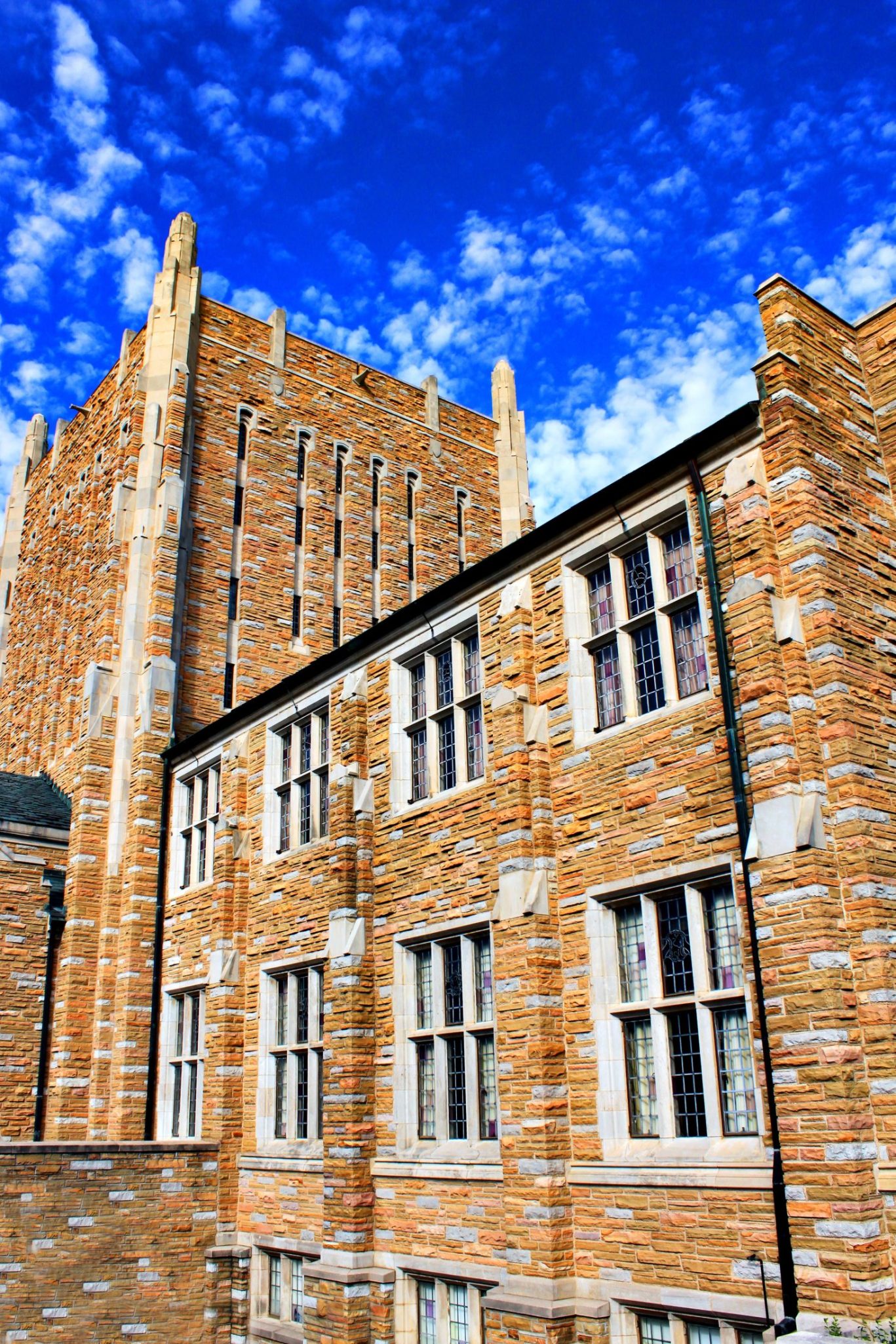 Historic stone university building with tall windows and blue sky backdrop.