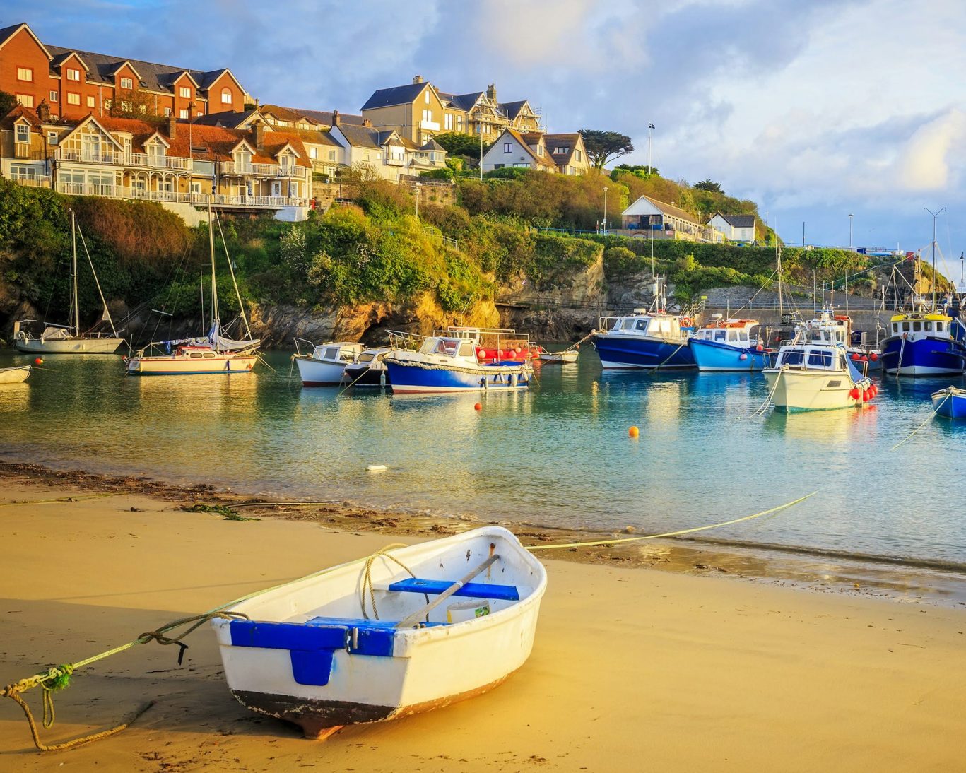 Charming seaside village with colorful boats moored in the harbor and houses on the hill.