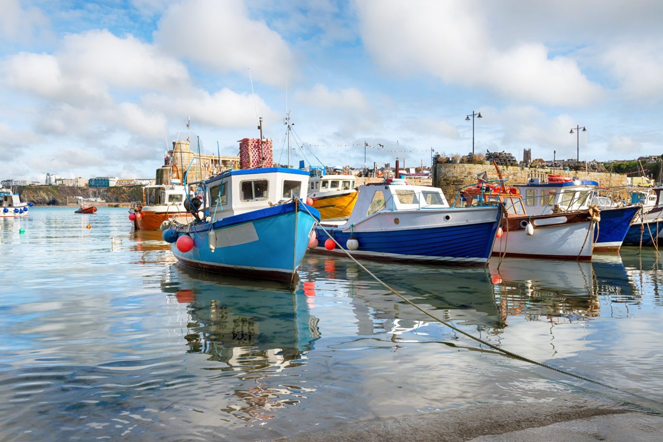Colorful fishing boats docked in a peaceful harbor on a clear day with reflections in the water.
