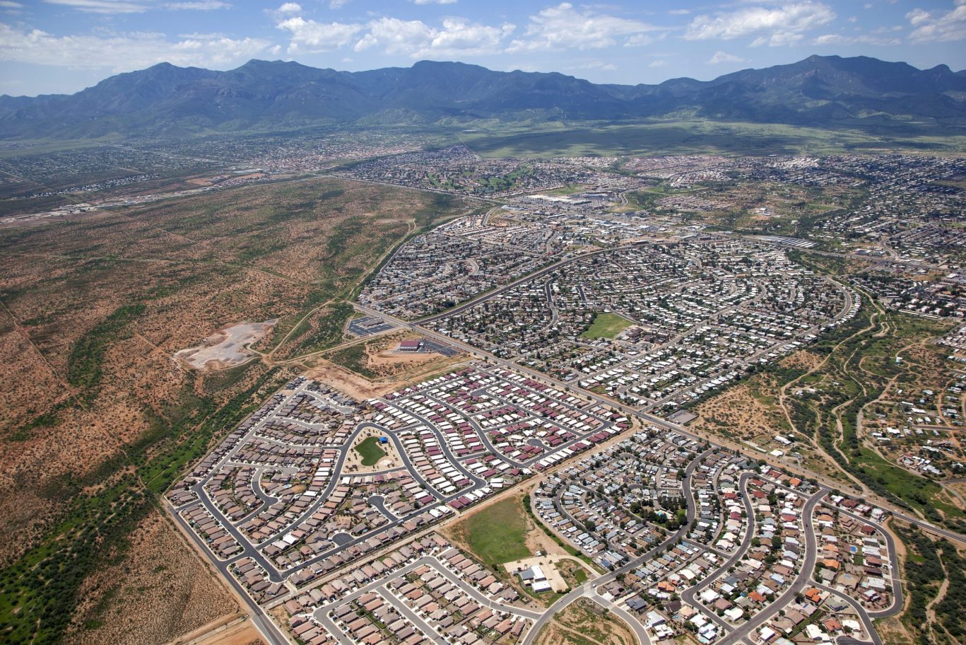 Aerial view of suburban neighborhoods and desert landscape in Sierra Vista, Arizona with mountain range in the background.