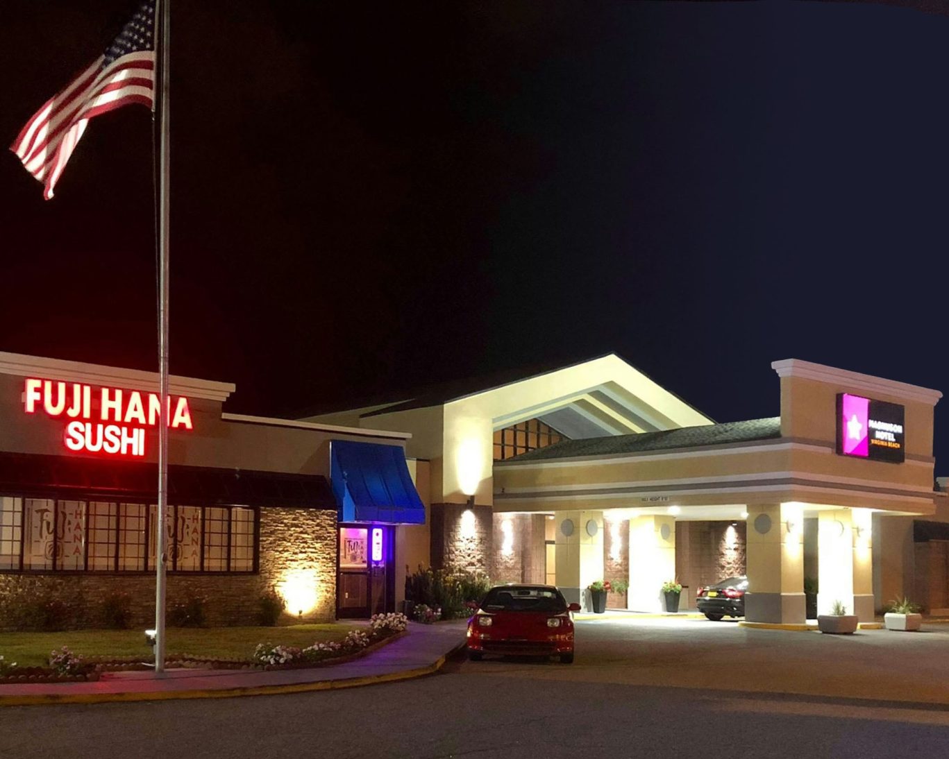 Hotel exterior at night with illuminated Fuji Hana Sushi sign and American flag.