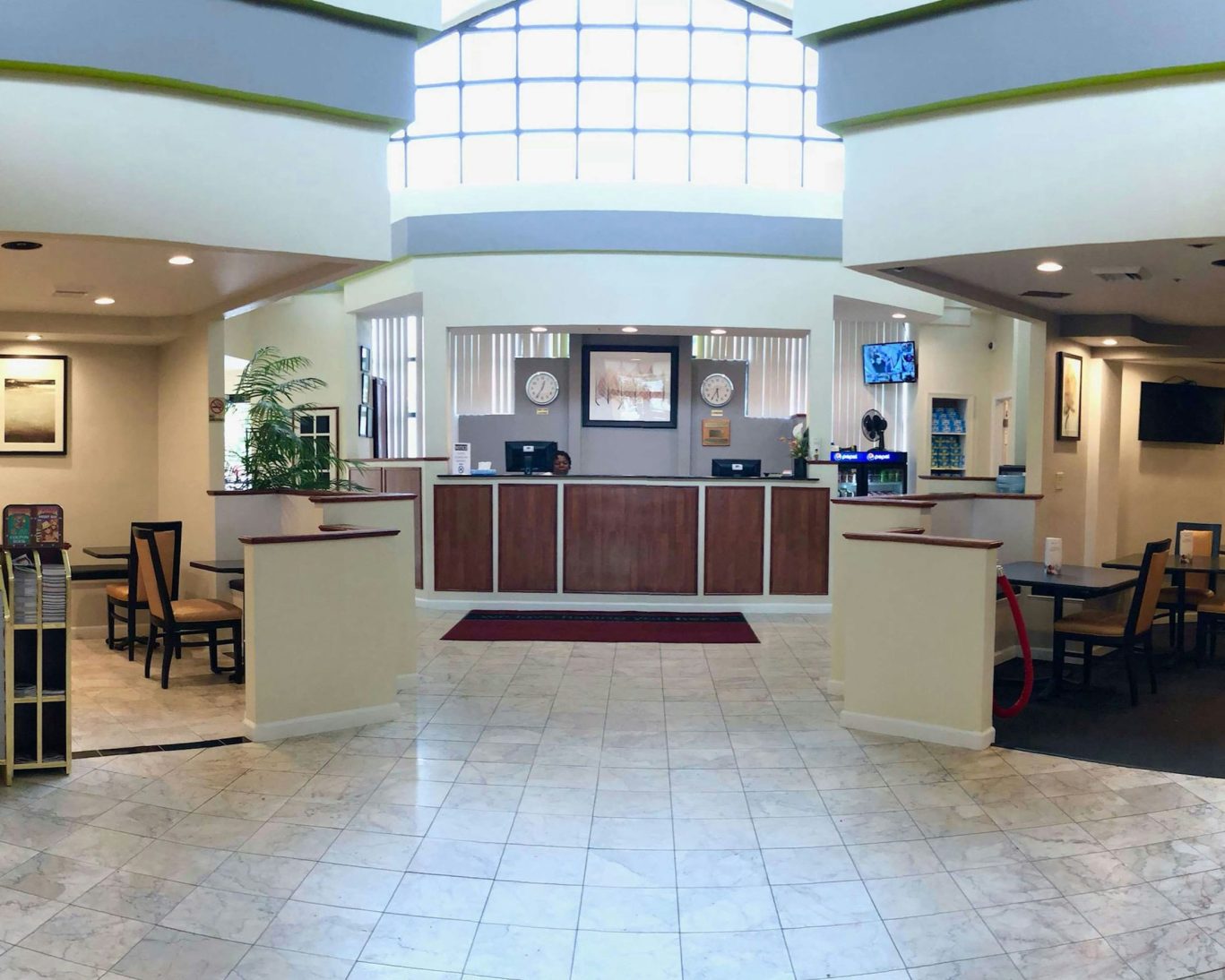 Spacious hotel lobby with front desk, seating area, and high arched windows.